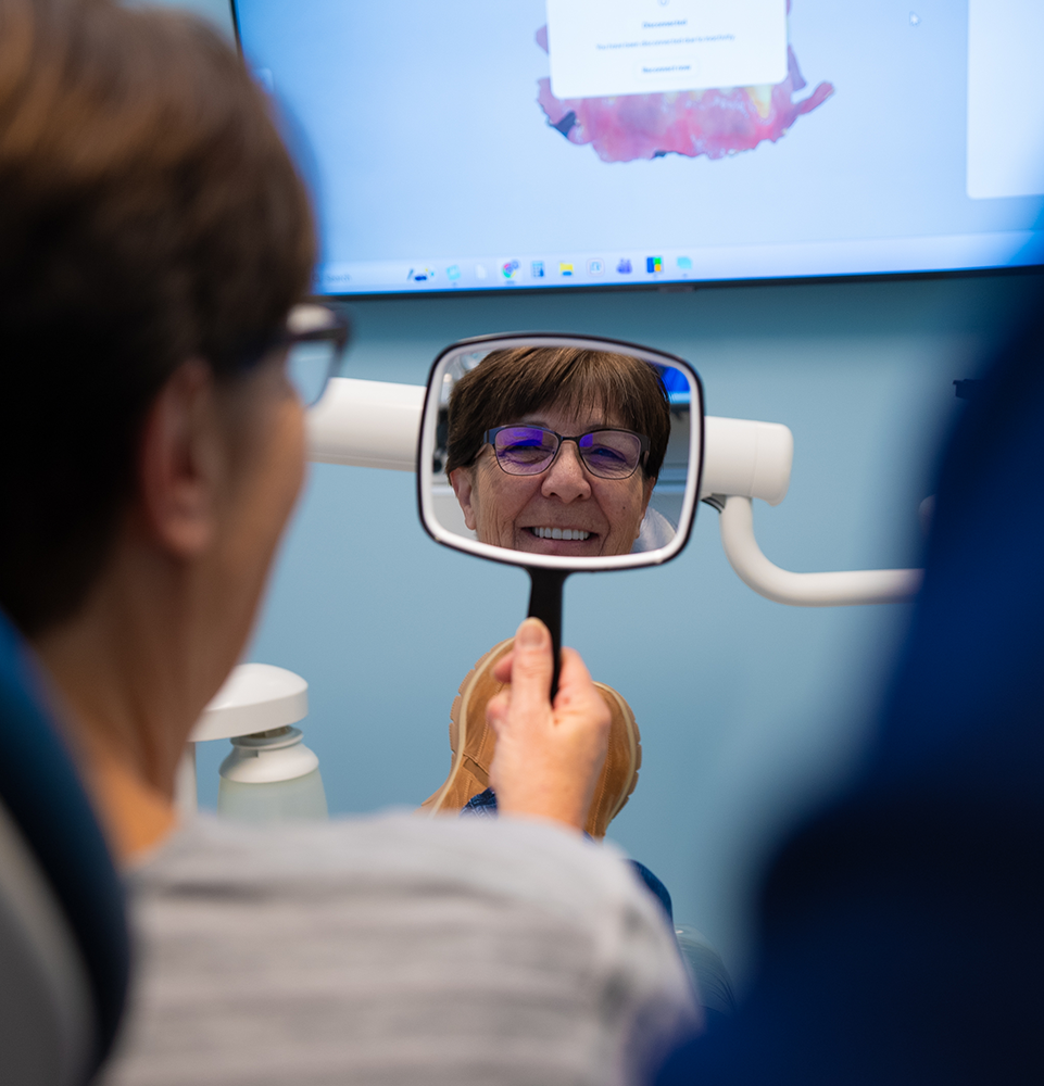 patient holding a dental mirror and smiling
